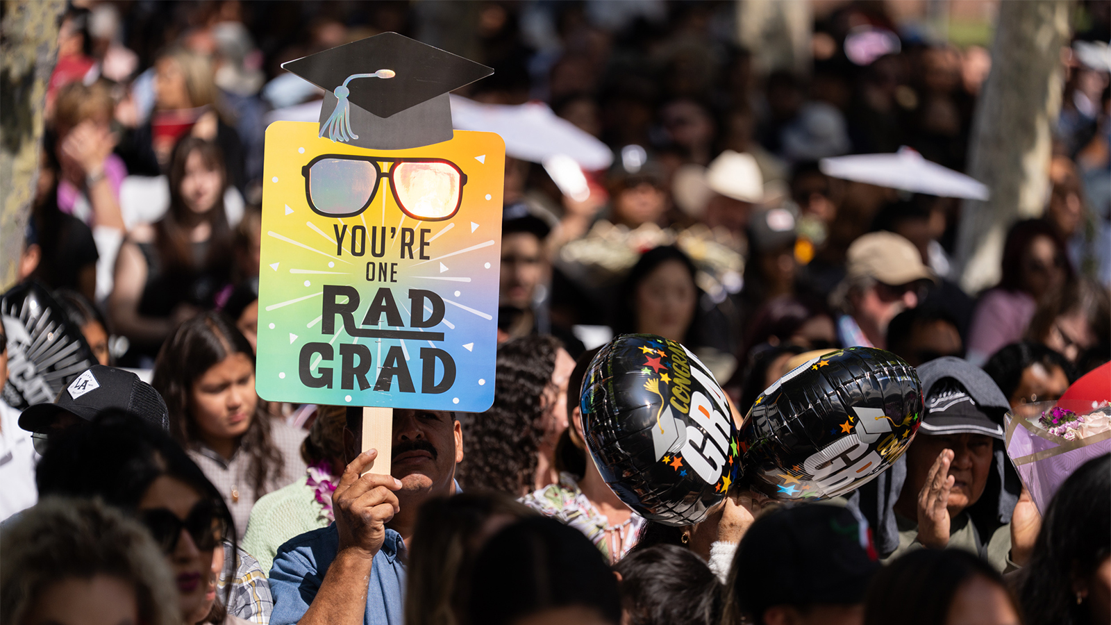 People on the public during Commencement with a graduation banner