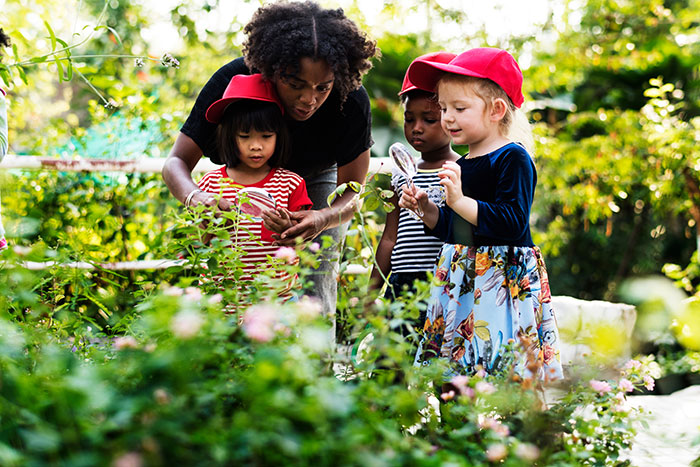Young black woman in garden with three pre-school aged children