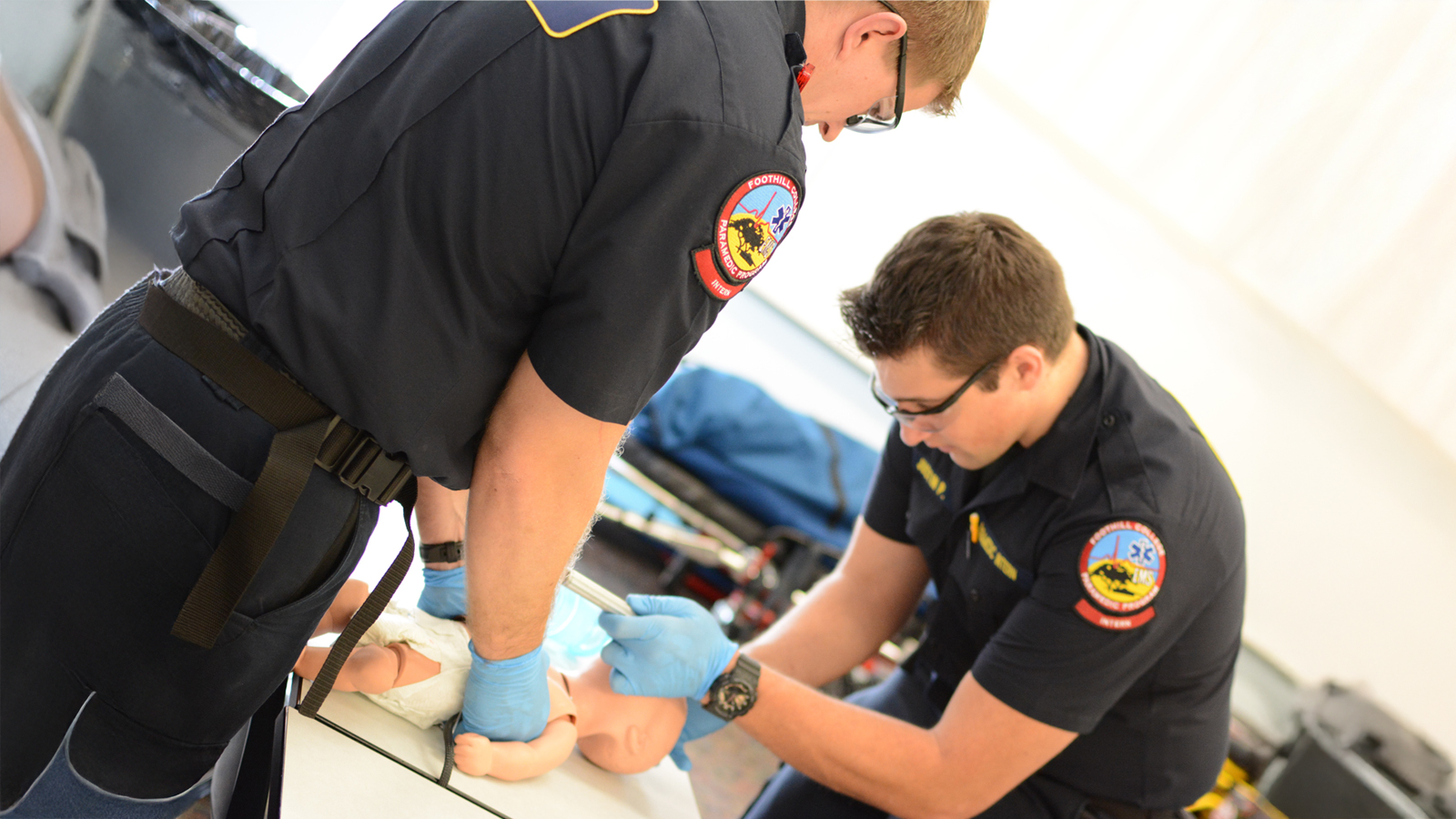 Male paramedic students practicing at class with a baby dummy 