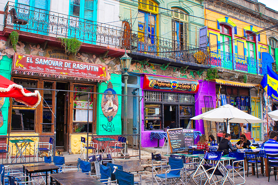 Buenos Aires street with a couple of restaurants and tables and chairs outside like a plaza