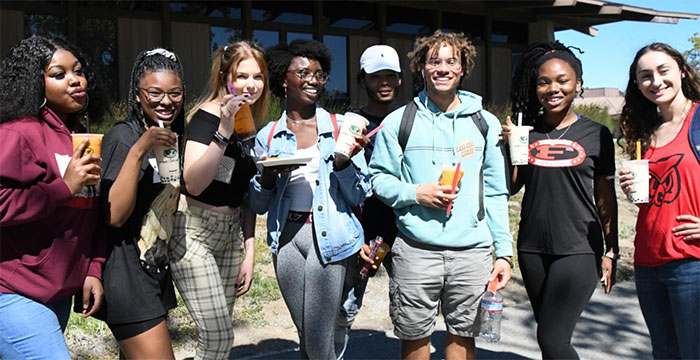 a group of diverse students drinking boba tea in front of building