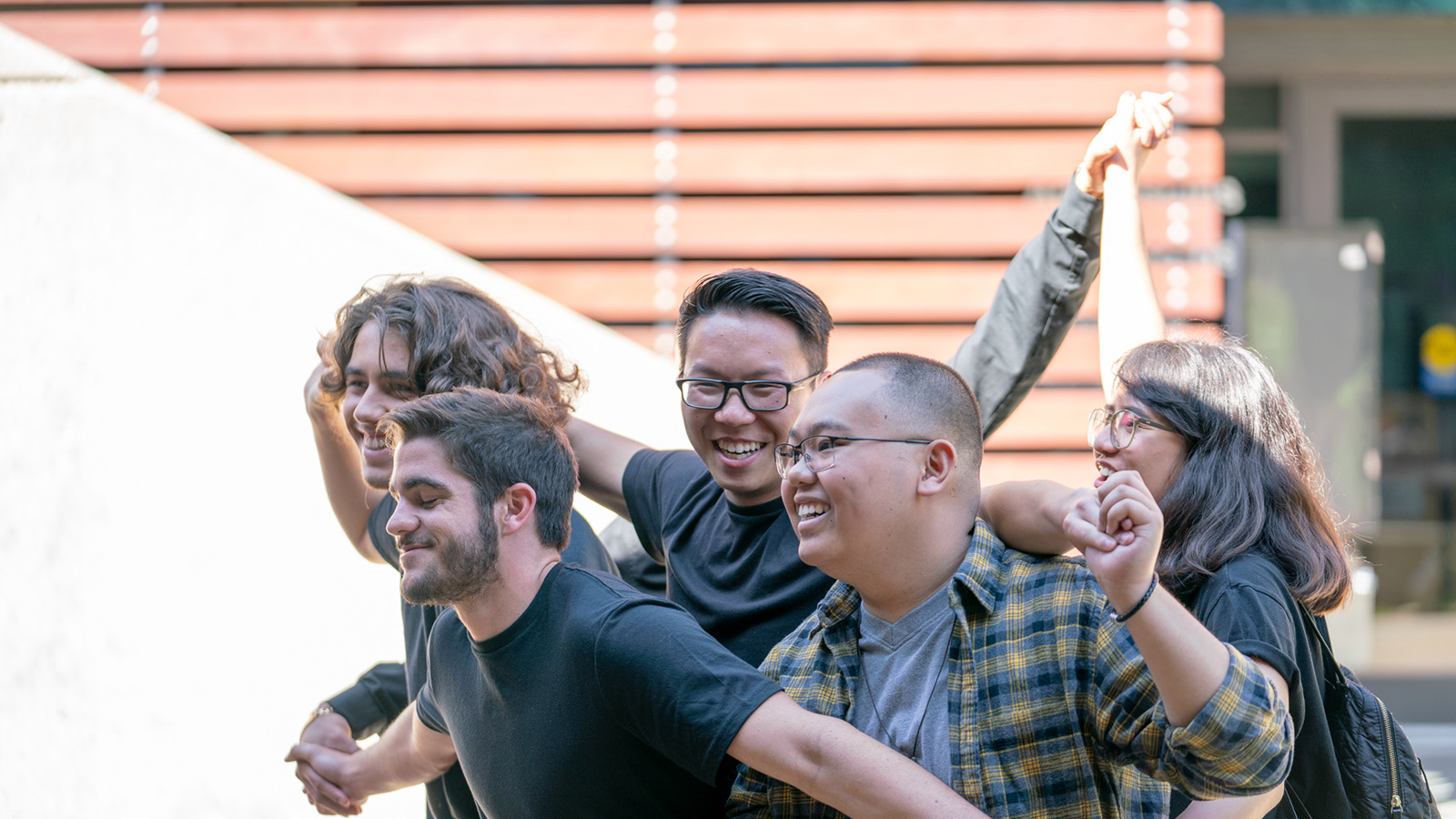 Group of college students smiling and celebrating together outdoors on campus.