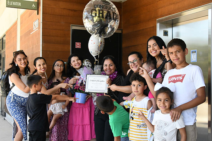 students holding certificate surrounded by family member