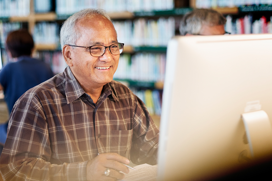 Adult learner using a desktop computer in the library