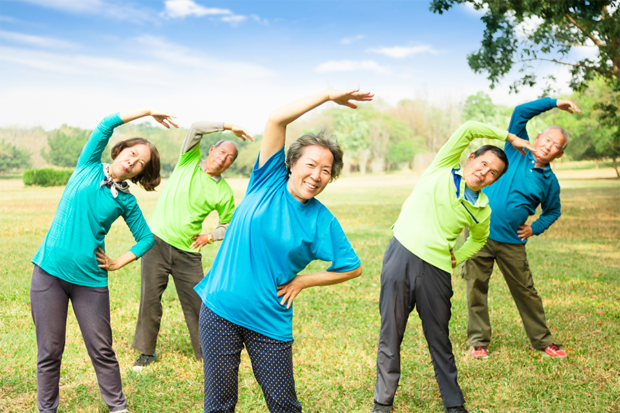 Group of adults stretching together during an outdoor fitness class