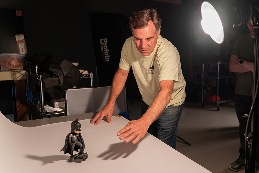 Student adjusting lighting while photographing a small object in a photography studio
