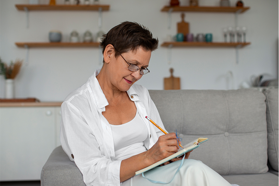 Adult learner writing in a notebook while studying at home