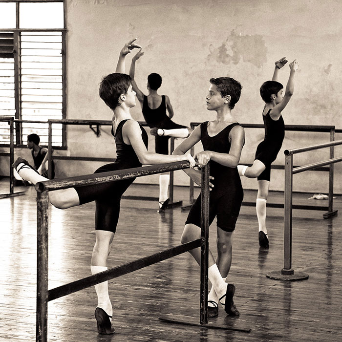 Four young male ballet dancers at barre