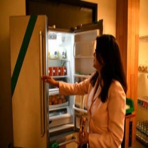 President Thuy Thi Nguyen opens a refrigerator door to the food pantry where fresh produce and dairy products are stocked for students experiencing food insecurity. 