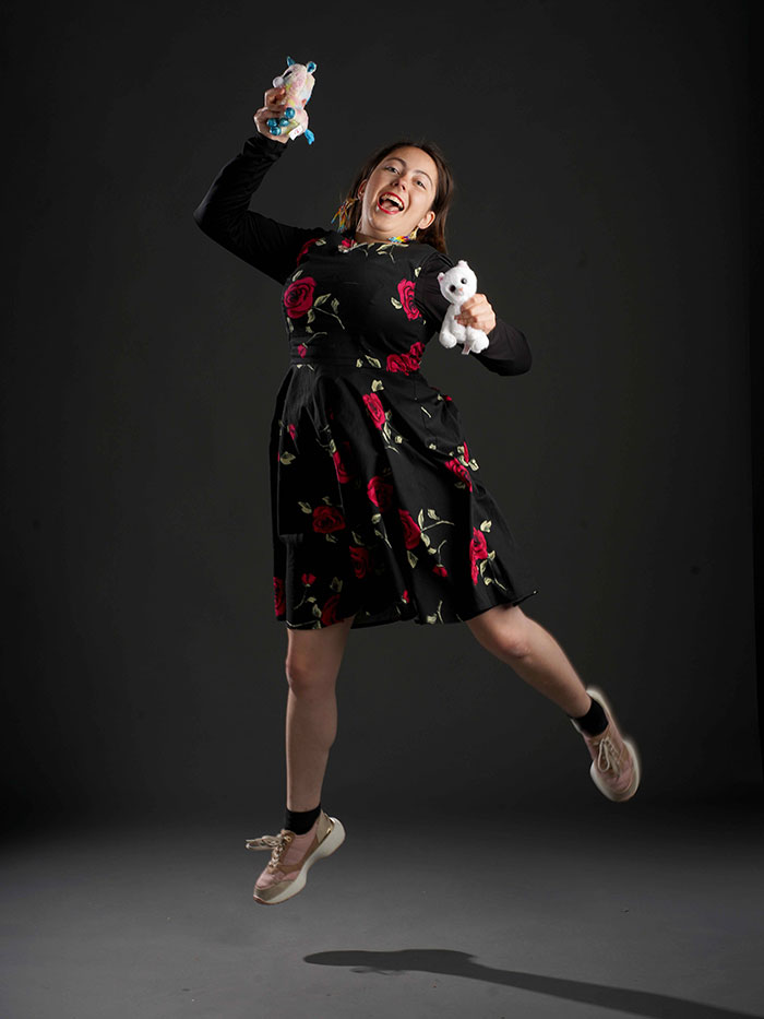 TTW student photoshot - a female student jumping with dolls in their hands