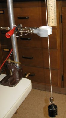 Photo shows a string going through a coil of wire.  A magnet is dropped down the string and the chaning magnetic field at the point of the coil is detected via a current through the coil.
