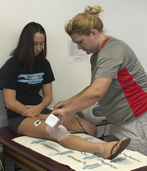 Student wrapping athlete's leg